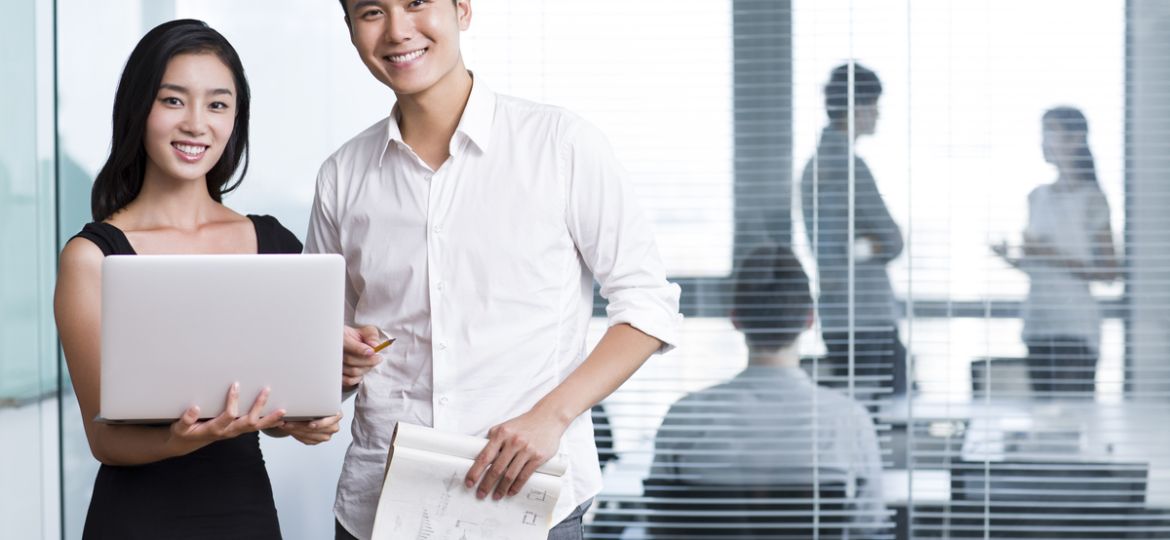 Happy Chinese business people with laptop